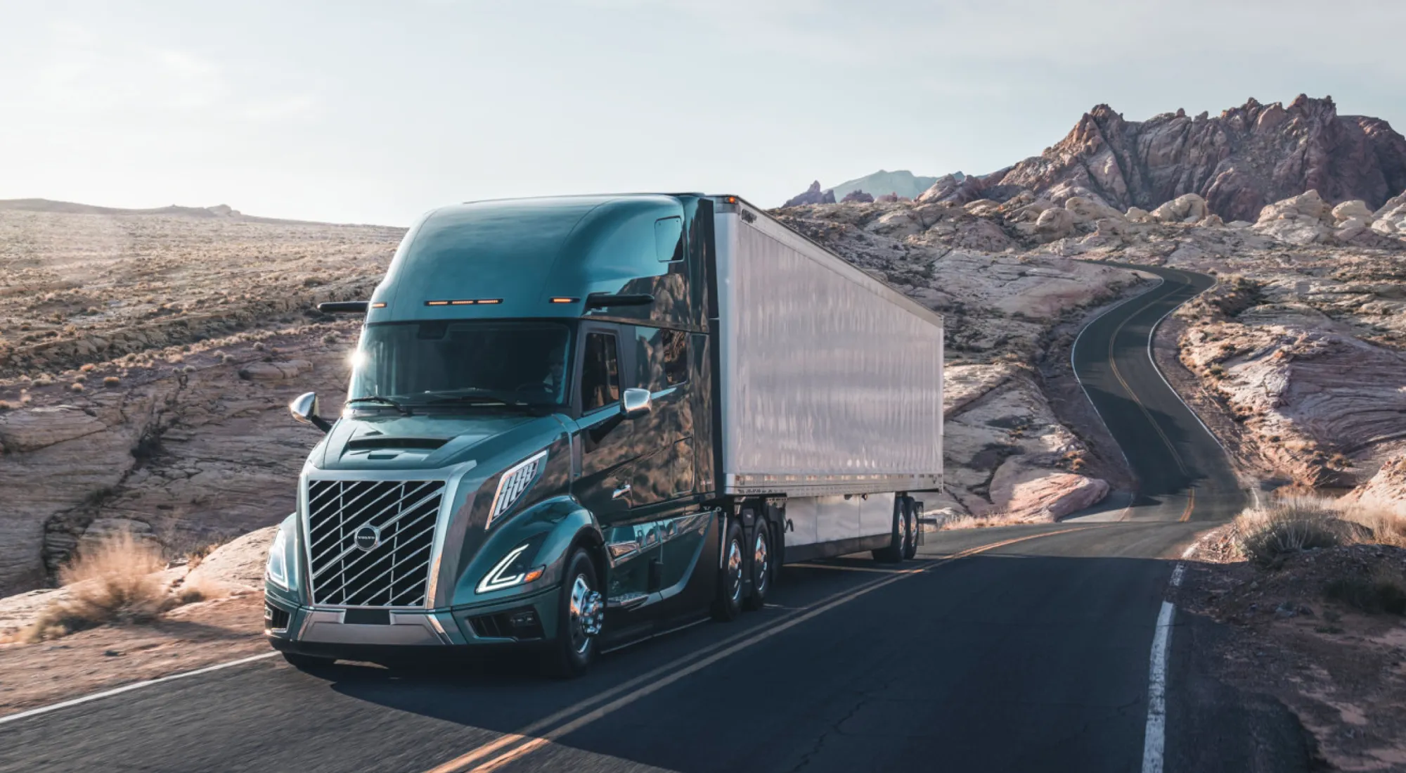 2027 Volvo VNL64T860 tractor with a dry van trailer on an open desert highway
